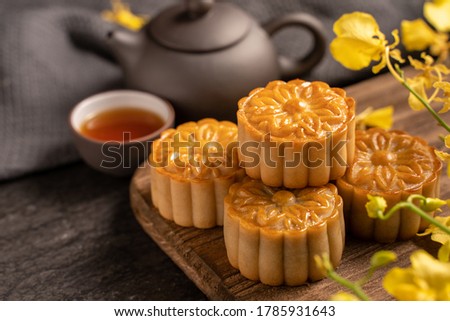 Mooncake, Moon cake for Mid-Autumn Festival, concept of traditional festive food on black slate table with tea and yellow flower, close up, copy space. Royalty-Free Stock Photo #1785931643