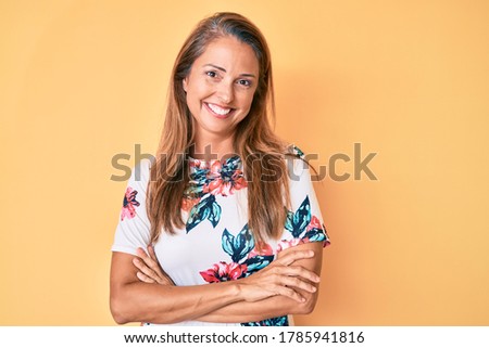 Middle age hispanic woman wearing casual floral dress happy face smiling with crossed arms looking at the camera. positive person. 