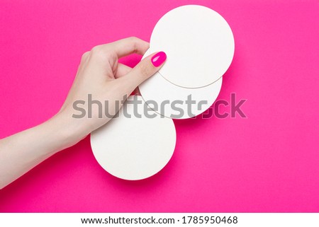 Female hand holding several empty coasters on pink background