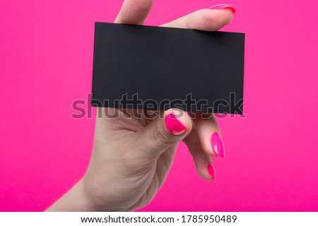 Woman's hands hold blank business card isolated on pink paper. Close up shot