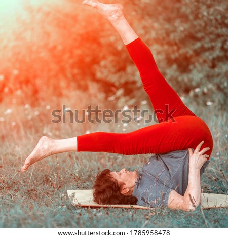 beautiful mature women with doing yoga in forest park On a summer day.