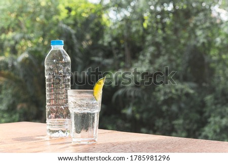 Refreshing drink glass of water with slice of lime on wooden table.