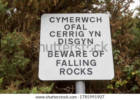 Sign warning visitors to beware of falling rocks on The Great Orme at Llandudno in North Wales, written in both English and Welsh 