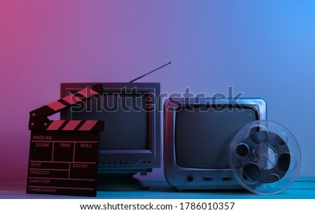 Old tv receivers with movie clapperboard, film reel in red blue neon light. Entertainment Industry, Media 80s