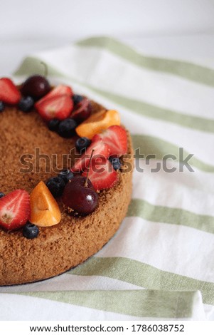Delicious brown birthday cake with summer fruits and berries on top, close up.