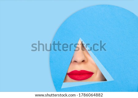 Calm. Close up female red lips peeks throught triangle in blue background. Trendy geometrical style, copyspace. Vibrant colors. Hidden emotion, make up. Sales, proposal, finance and business concept.