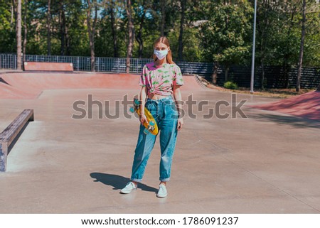 Outside in a urban skate park stylish lady asian looking with a creative protective mask in front of the camera looking straight concept of Covid-19