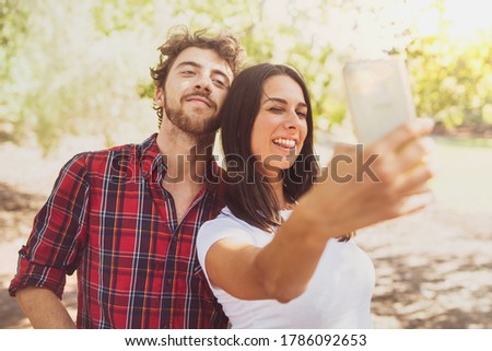 Couple of friends taking a selfie in the countryside. Young people having fun taking pictures with the smartphone for social network sharing.