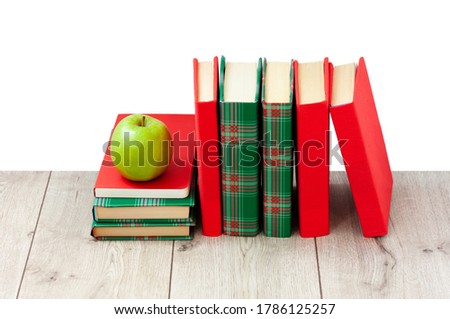 Back to school, pile of books in colorful covers and green apple on wooden table with white background. Distance home education. Quarantine concept of stay home