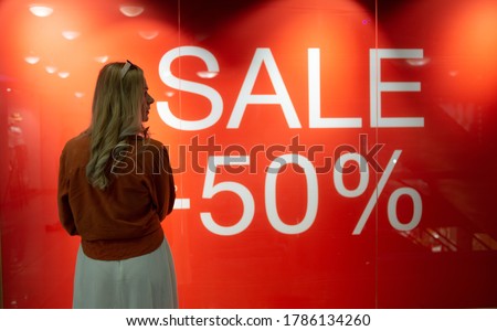 female silhouette in front of a banner. Discount labels at the entrance to the store. Sale up to 50 percent. Shopping center. Seasonal Sale,