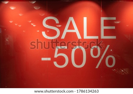 Large red sales poster at the entrance to a retail sale of clothing. Discount labels at the entrance to the store. Sale up to 50 percent. Seasonal Sale