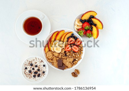 Summer breakfast with granola, tea, yoghurt and berries on a light background. Flatlay.