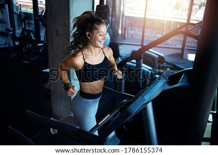 Top view of smiling woman exercising and training in the gym on treadmill running machine. Healthy lifestyle and positive people. Royalty-Free Stock Photo #1786155374