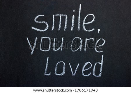 Chalkboard text "smile you are loved". Motivating inscription