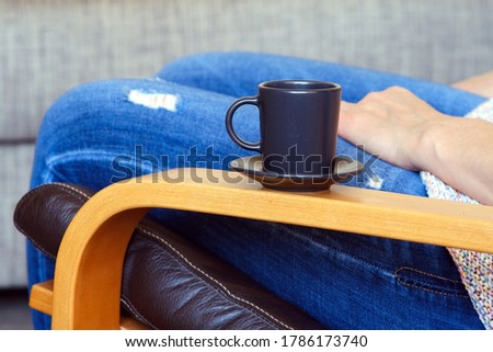 Rocking chair at your leisure. Girl holds a cup of coffee in her hands. Warms your hands. We are sitting in an armchair, at home in quarantine.