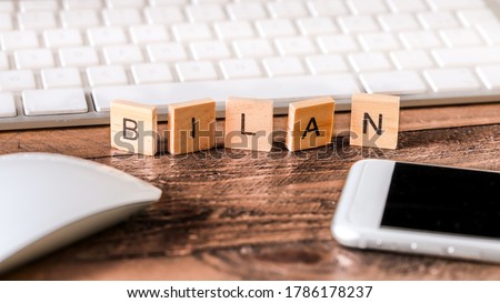 Letters on wooden pieces concept, business background, french word "bilan" means balance sheet