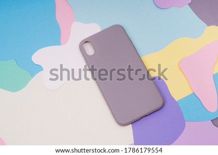 The gray silicone case for the smartphone lies on a multi-colored background. Protect your phone.
