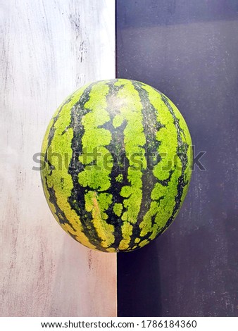 green ripe watermelon isolated on a half black, half silver background
