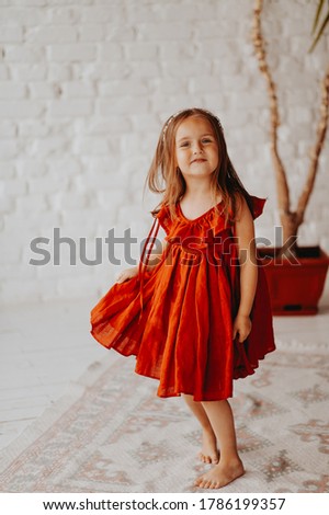 little girl of five years in a red dress in a white interior, summer photos, with a watermelon in her hands
