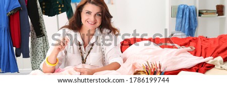 Portrait of smiling seamstress looking at camera with smiling. Fashion designer making fashionable dress. Process of designing stylish clothes. Atelier and family business concept