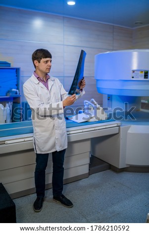 Doctor holding a picture of a brain MRI workflow in diagnostic hospital. Healthcare, roentgen, people and medicine concept.