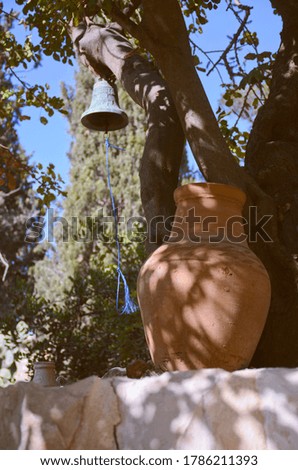 Clay jug and bell on stone wall in the courtyard. Vertical photo of rural life