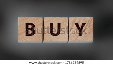 Wooden Text Block with word BUY on black background. Trading business concept.