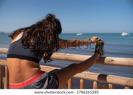 Young girl streching on stick on the beach with sporty clothes
