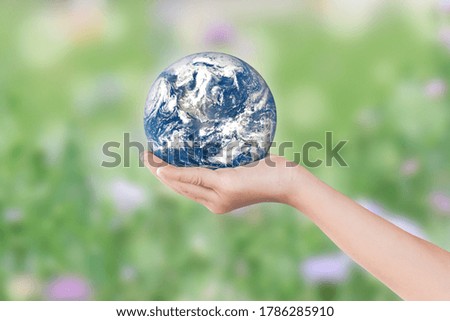 Environment day concept: Child hands holding earth over blurred green nature background. Elements of this image furnished by NASA