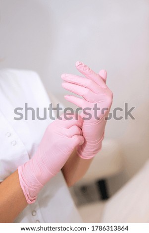 Hand in a pink latex medical gloves. Preparation for work in the master's office