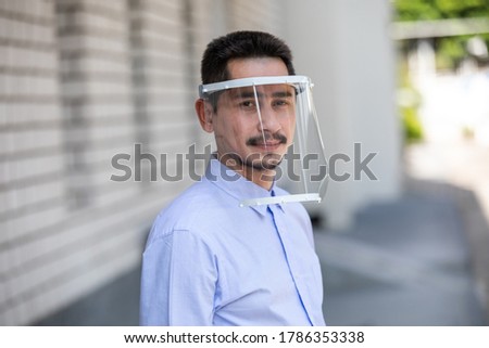 Asian young man wearing face shield for healthcare which is required for doctor and general public to prevent COVID-19.