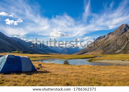 A tent pitched beside the Ahuriri River, surrounded by mountains, in Cantebury, South Island, New Zealand Royalty-Free Stock Photo #1786362371