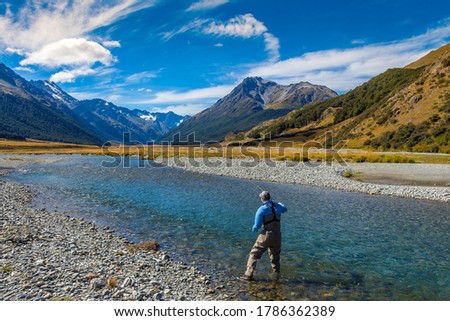 A fly fisherman casting on a beautiful mountain stream in New Zealand's South Island, Ahuriri River, Omarama Royalty-Free Stock Photo #1786362389