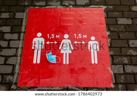 A crumpled protective mask lies on a red sign that informs people to keep a social distance. Sign informing people to keep 1,5 meter distance from each other, prevent spreading Coronavirus infection