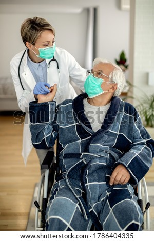 Senior man in wheelchair talking to female doctor who is visiting him during corona virus quarantine. 