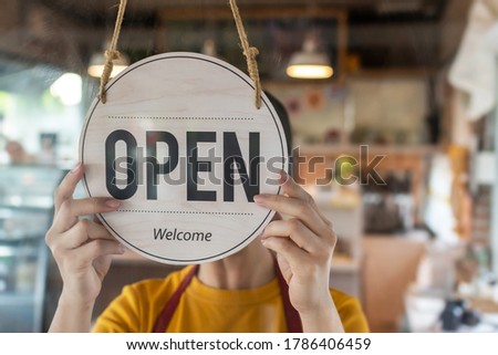 Restart. waitress woman wearing protection face mask turning Open sign board reopen after coronavirus quarantine is over in cafe coffee shop ready to service, cafe restaurant, food and drink concept