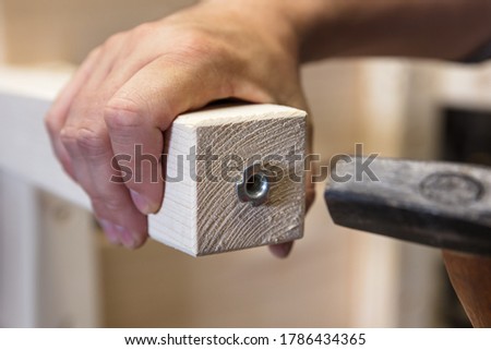 Man is installing a adjustable variable screw in a wooden desk or table leg