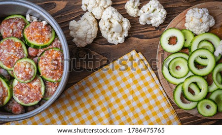Fresh green striped zucchini cut into circles prepared for stuffing with a mixture of meat and vegetables, on a cutting Board. Wooden rustic table background. Copy of the space.
