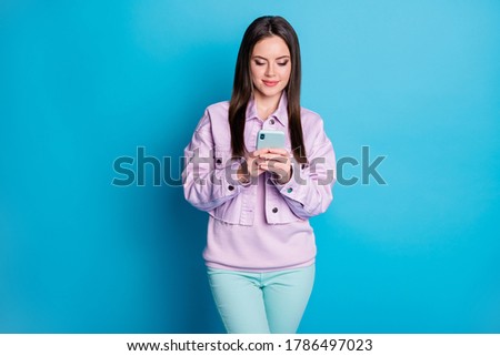 Photo of pretty charming lady hold telephone hands browsing blog online website writing new post wear casual denim violet jacket sweater trousers isolated blue color background