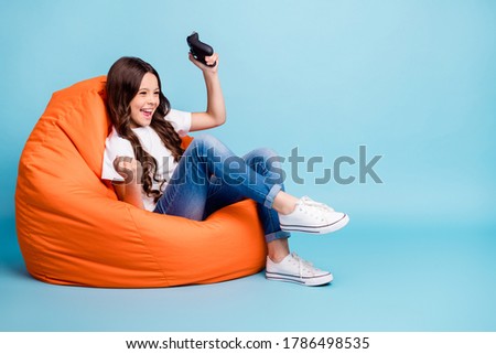Portrait of her she nice attractive cheerful excited glad wavy-haired girl sitting in chair playing online game win isolated on bright vivid shine vibrant blue teal turquoise color background
