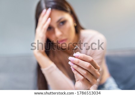 Young woman holding wedding engagement ring in hands, engaged girl doubts about marriage proposal, abandoned wife depressed after getting divorced, help to overcome breaking up, starting new life