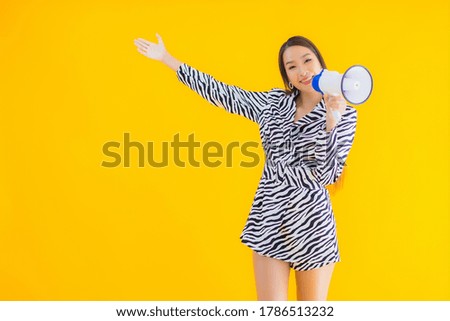Portrait beautiful young asian woman smile happy with megaphone on yellow isolated background