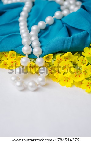 Bright little yellow flowers with a pearl bracelet. Stock photo for tailor and designer