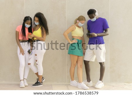 Young people group with face mask waiting to get in the supermarket.  Multiracial people looking videos. Coronavirus and spread virus prevention concept. Image