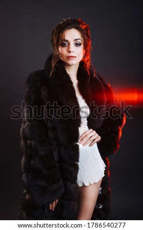Fashion studio portrait of beautiful lady with elegant hairstyle in dark brown luxury natural faux fur coat. Winter beauty in luxury. Fashion fur.  model posing in fur coat expressing confidence

