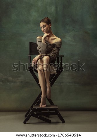 Beautiful portrait. Graceful classic ballerina dancing, posing isolated on dark studio background. Stylish trench coat. Grace, movement, action and motion concept. Looks weightless, flexible.