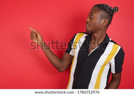 Smiling African american man with braids wearing casual shirt over isolated red background pointing up and looking at the camera 