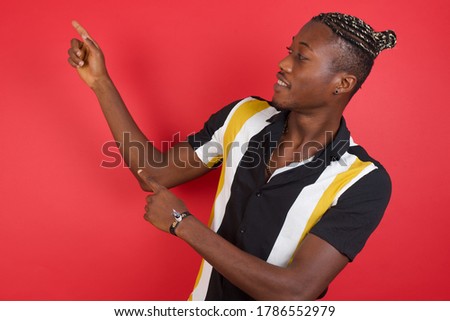 African american man with braids wearing casual shirt over isolated red background indicating with forefinger empty space showing best low prices 