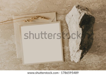 Craft envelope, blank greeting card, stone and wheat branch on a marble table. Flat lay, top view. Rustic autumn composition. 