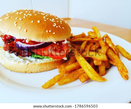 Burger with bacon, lettuce, tomato, and red onion, served with fries